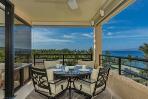 A round table with chairs on a balcony overlooking a coastal view. - Polo Beach Club 703 2 Bedroom Condo (Kihei)