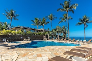 A pool area with lounge chairs, a stone pool, and palm trees. - Polo Beach Club 703 2 Bedroom Condo (Kihei)