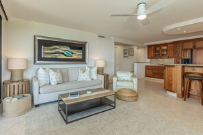 A living room with a sofa, coffee table, and a painting on the wall. - Polo Beach Club 703 2 Bedroom Condo (Kihei)