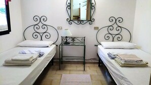 A room with two single beds, a small table with a lamp, a mirror on the wall, and a window. - Villa Claudia Residence I Mandorli (Villaggio Mandorli)