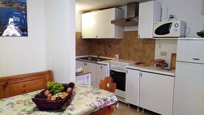 A compact kitchen with a bed, a fruit basket, and a microwave. - Villa Claudia Residence I Mandorli (Villaggio Mandorli)