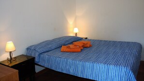 En säng med en blå, randig sängkappa, två sänglampor och en orange handduk på sängen.