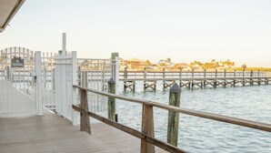 Un muelle de madera con valla blanca y un cartel que indica paso de peatones.
