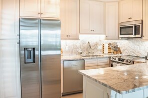 Una cocina moderna con electrodomésticos de acero inoxidable, encimeras de mármol y armarios de tonos claros.