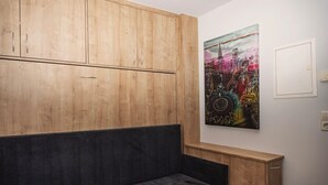 A room with a wooden wardrobe, a grey bench, and a colorful abstract painting on the wall. - Soothing 1-bedroom studio in charming Stuttgart perfect for your stay W3_P13 (Stuttgart)