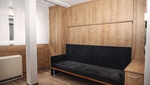 A room with a wooden wardrobe, a black sofa, and a radiator. - Soothing 1-bedroom studio in charming Stuttgart perfect for your stay W3_P13 (Stuttgart)