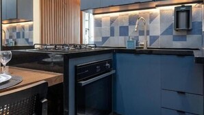 Une cuisine moderne avec des armoires bleues, une cuisinière encastrée et un coin repas avec une chaise noire.