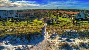 A resort with multiple-story buildings, a central courtyard with palm trees, and a sandy beach area. - New Listing! Third Floor Condo Close to Beach With Pool Views. (Saint Augustine)