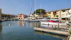 Un port de plaisance avec des bateaux amarrés, une jetée en bois et, au fond, des bâtiments dotés de balcons.