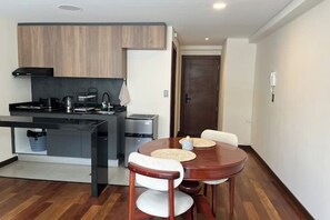 A compact kitchen with modern appliances, a dining area with a wooden table and chairs, and a small island with a sink. - Modern and cozy studio apartment in La Paz (La Paz)