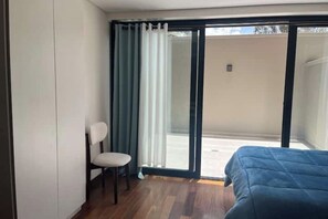A room with a bed, a chair, and a sliding glass door leading to an outdoor area. - Modern and cozy studio apartment in La Paz (La Paz)