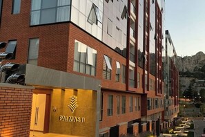 A modern building with a prominent "PALMAS II" sign, featuring a mix of brick and glass facade, and a flat roof.