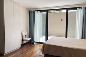 A bedroom with a bed, a chair, and a sliding glass door leading to an outdoor area.