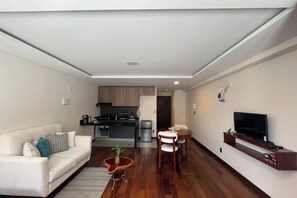 A modern living room with a sofa, a small coffee table, and a TV stand. - Modern and cozy studio apartment in La Paz (La Paz)