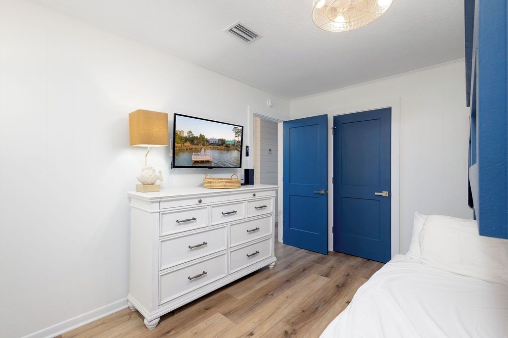 Une chambre avec une commode blanche, un lit et une porte bleue.