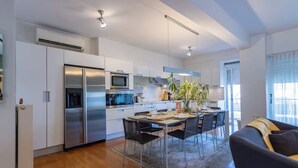 A modern kitchen with stainless steel appliances, a dining area with a table and chairs, and a large window providing natural light. - Urbanised Pangrati 2 bedroom Luxury (Athina)