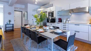 A modern kitchen with white cabinets, a dining area with a table set for four, and a large potted plant. - Urbanised Pangrati 2 bedroom Luxury (Athina)