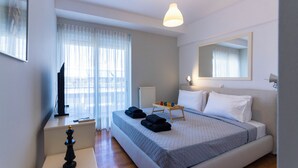 A hotel room with a bed, a TV, a chessboard, a tray with towels, and a window with curtains. - Urbanised Pangrati 2 bedroom Luxury (Athina)