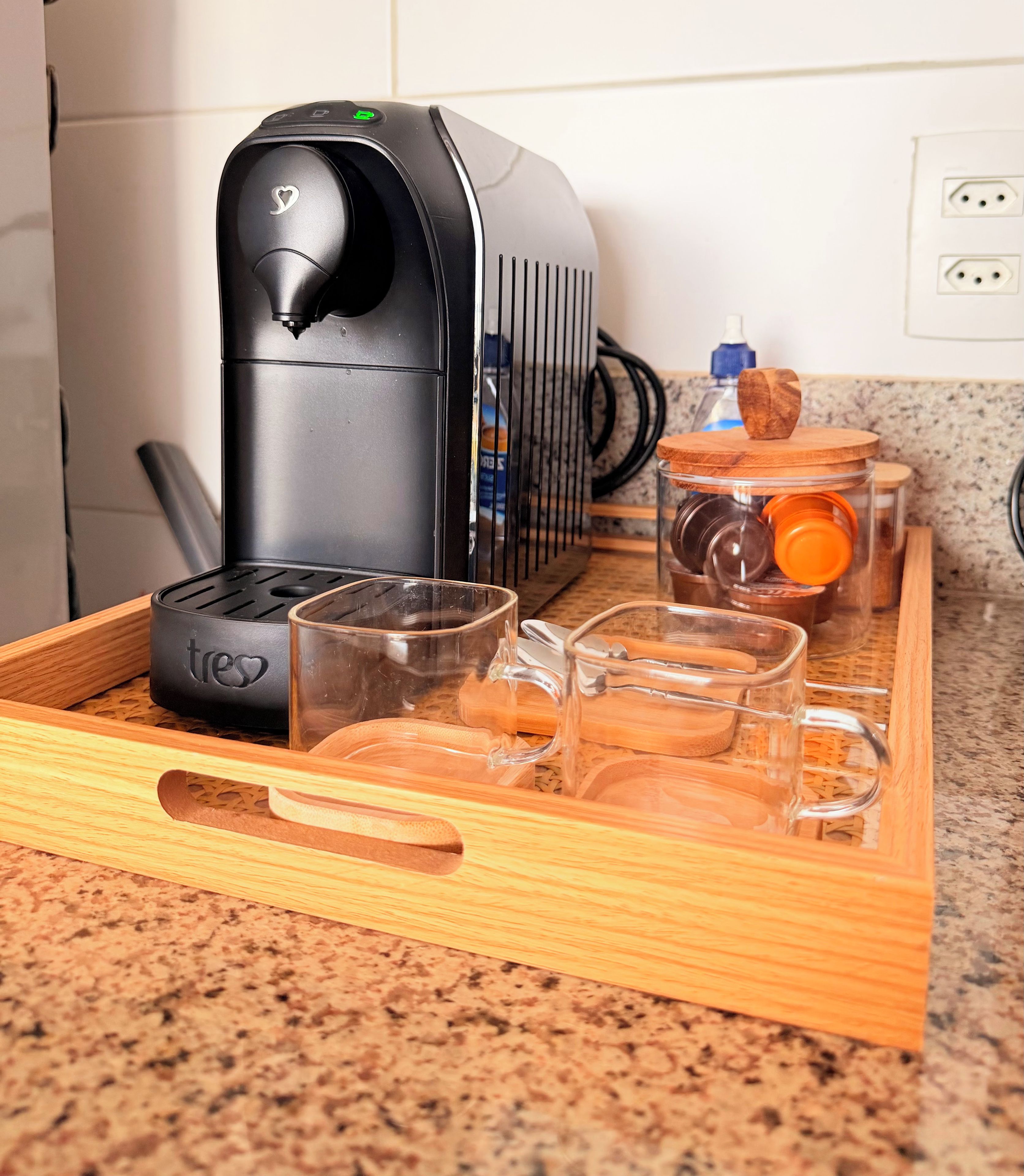 Un coin cuisine équipé d’une machine à café, d’un plateau avec des verres et d’une bouteille d’eau.