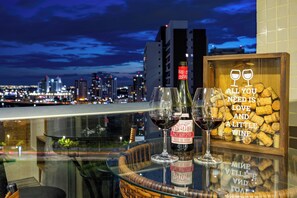 A cityscape view from a balcony with a table displaying wine bottles and glasses. - Lightness and Comfort: DFPlaza Shopping Águas Claras (Águas Claras)