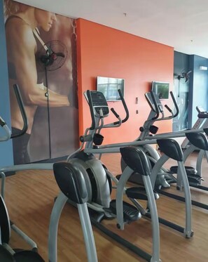 A gym with treadmills, a wall-mounted TV, and a large poster of a woman exercising. - Lightness and Comfort: DFPlaza Shopping Águas Claras (Águas Claras)