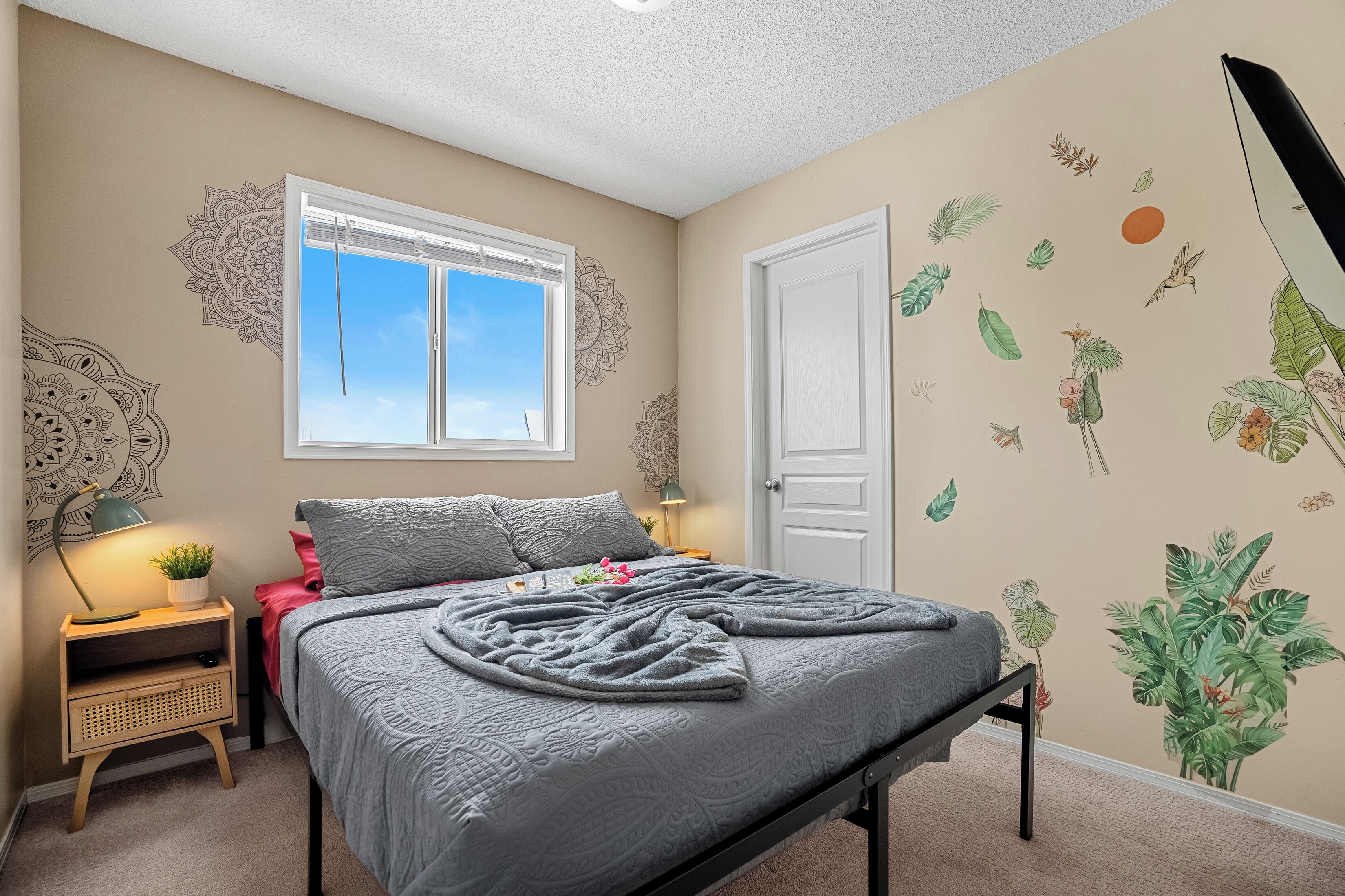 Quarto com cama, mesa de cabeceira, janela e porta.