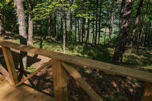 A wooden deck with a railing overlooking a forested area. - Grace Lodge – Mountain Cabin with Hot Tub & Stunning Views (Menlo)