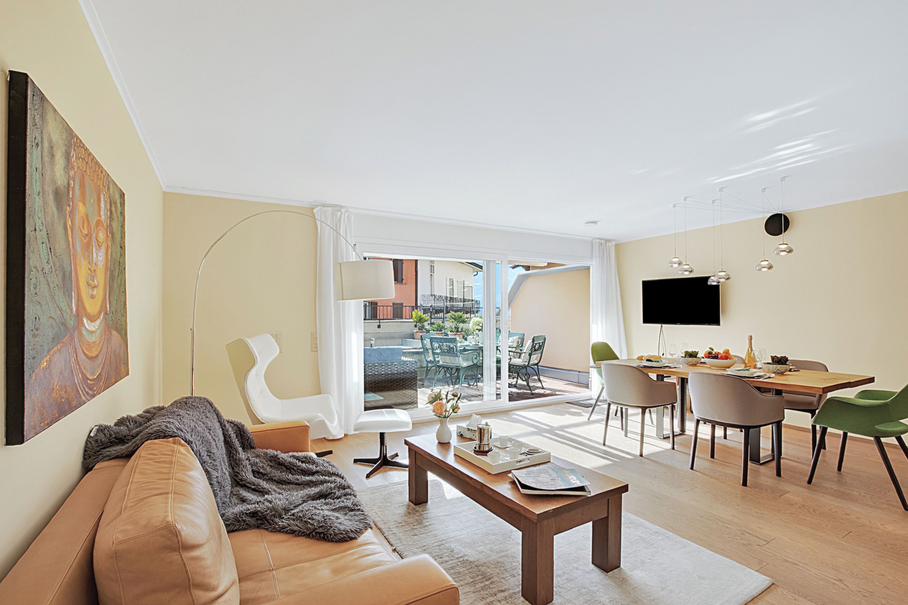 A modern living room with a sofa, coffee table, and dining area with chairs and a TV.