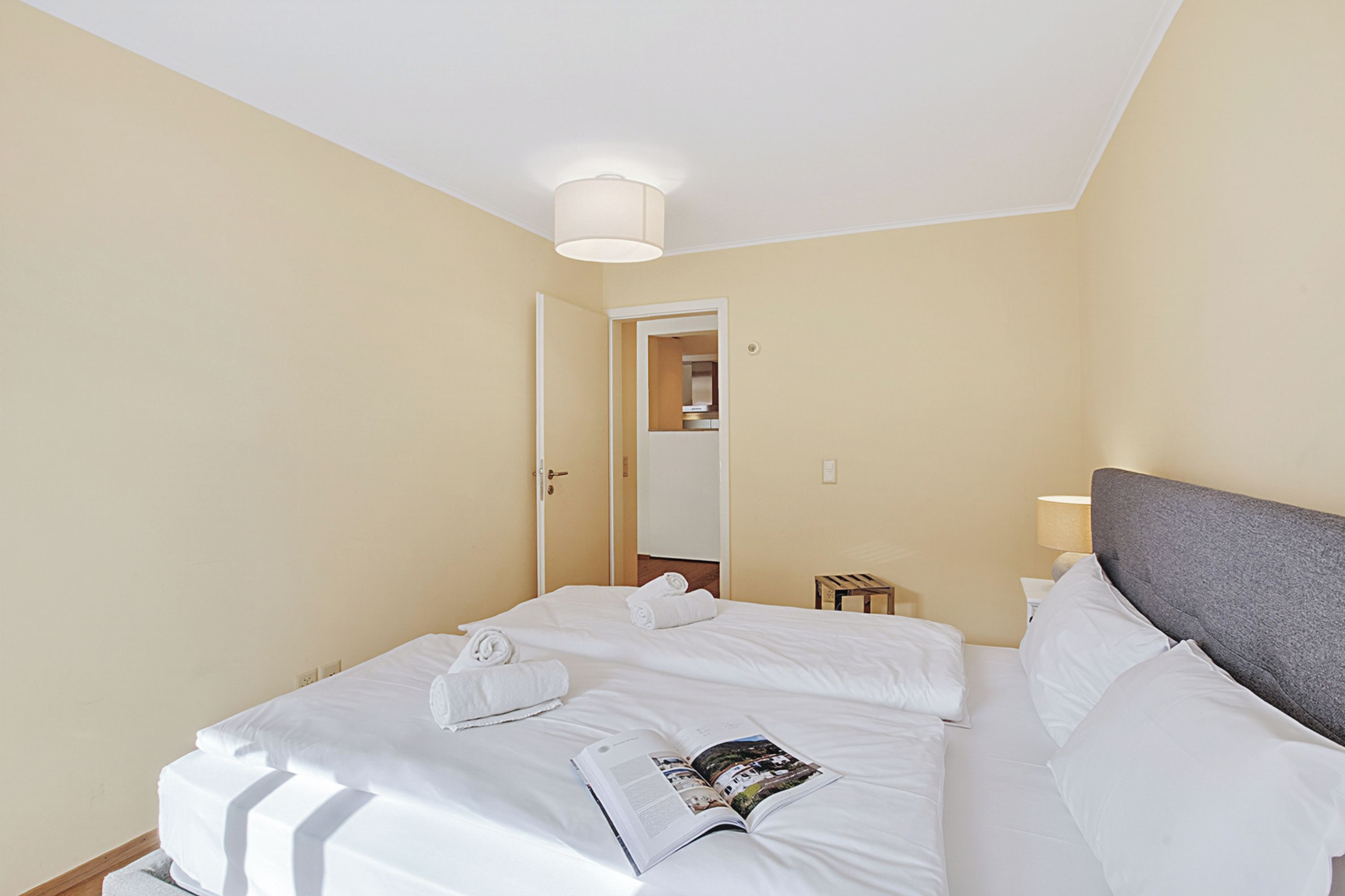 Une chambre d’hôtel comprenant un lit, une table de chevet, une lampe et une porte donnant sur une salle de bain.