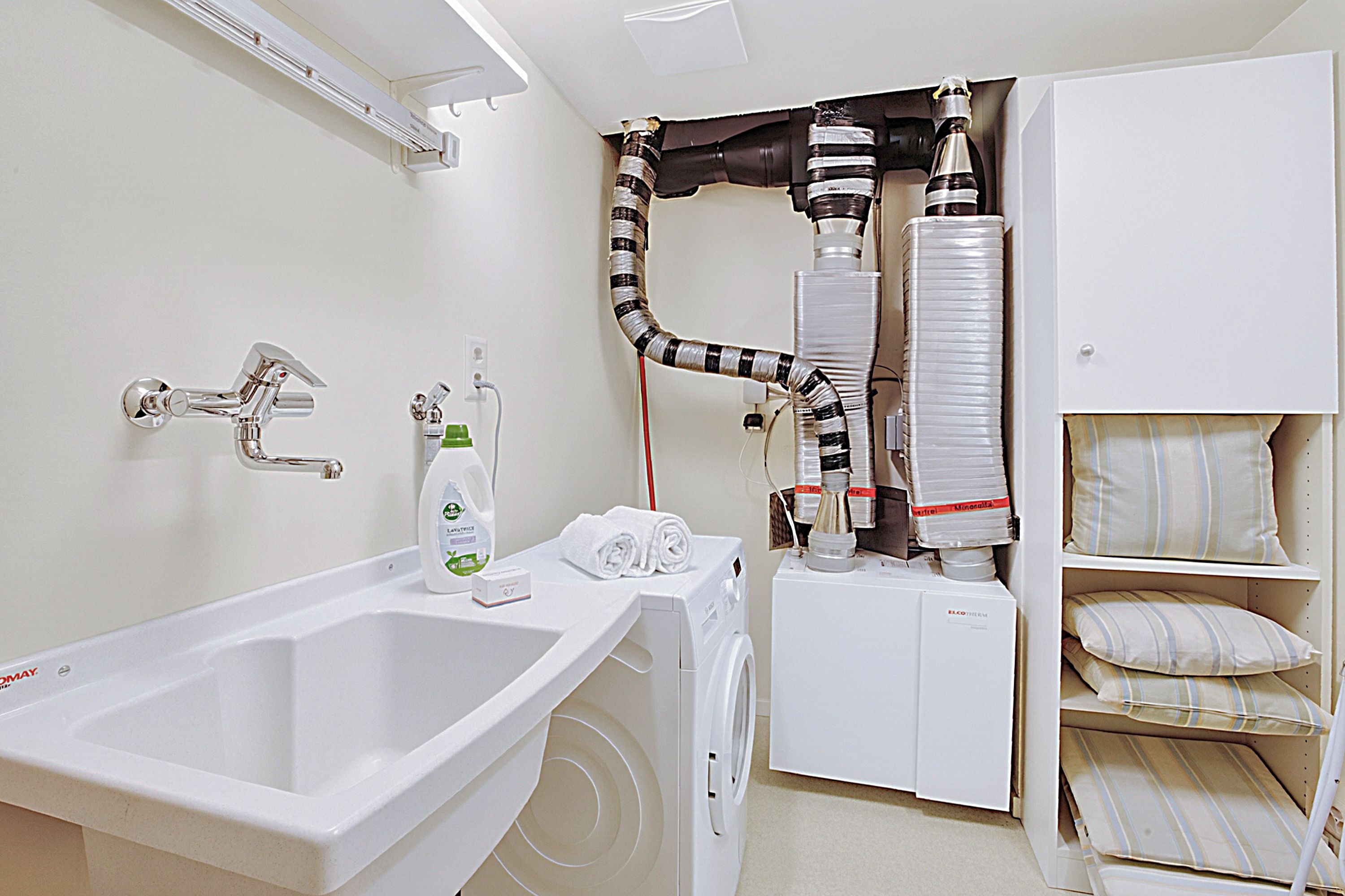 A modern bathroom with a large sink, a washing machine, and a storage cabinet.