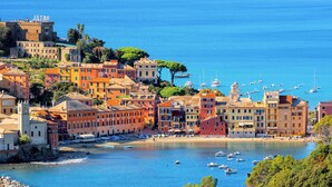 Una località costiera con edifici colorati, un porto turistico e una spiaggia.