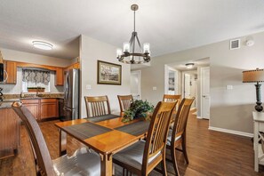 A dining area with a wooden table and chairs, a chandelier, and a kitchen in the background. - Two bedroom, two bathroom condo| Located in Pigeon Forge| Dollywood| Sleeps 6 (Pigeon Forge)
