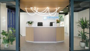 A reception desk with a modern design, a logo for 'ZEITRAUM Student Housing,' and potted plants on either side. - Zeitraum Raclawicka (Kraków)
