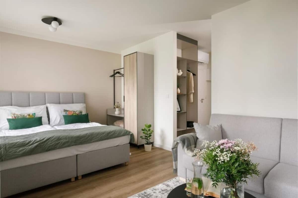A modern bedroom with a bed, bedside table, and a small seating area with a sofa and a coffee table.