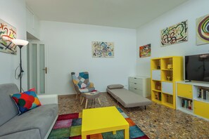 A modern living room with a sofa, a chair, a small table, a TV, and a bookshelf. - Bright & Stylish Flat near Villa Pamphili (Roma)