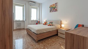 Een moderne slaapkamer met een houten bed, twee nachtkastjes, een radiator en een kunstwerk aan de muur.