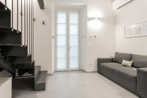 Ein modernes Interieur mit einer Treppe, einem grauen Sofa und einer Tür mit satinierten Glasscheiben.