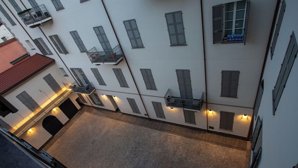 A courtyard with multiple balconies, a red-tiled roof, and a paved ground. - VOLTA COLLECTION BY HALLDIS (Como)