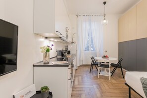 Habitación de hotel pequeña con kitchenette, zona de comedor, cama y vistas a la Torre Eiffel.