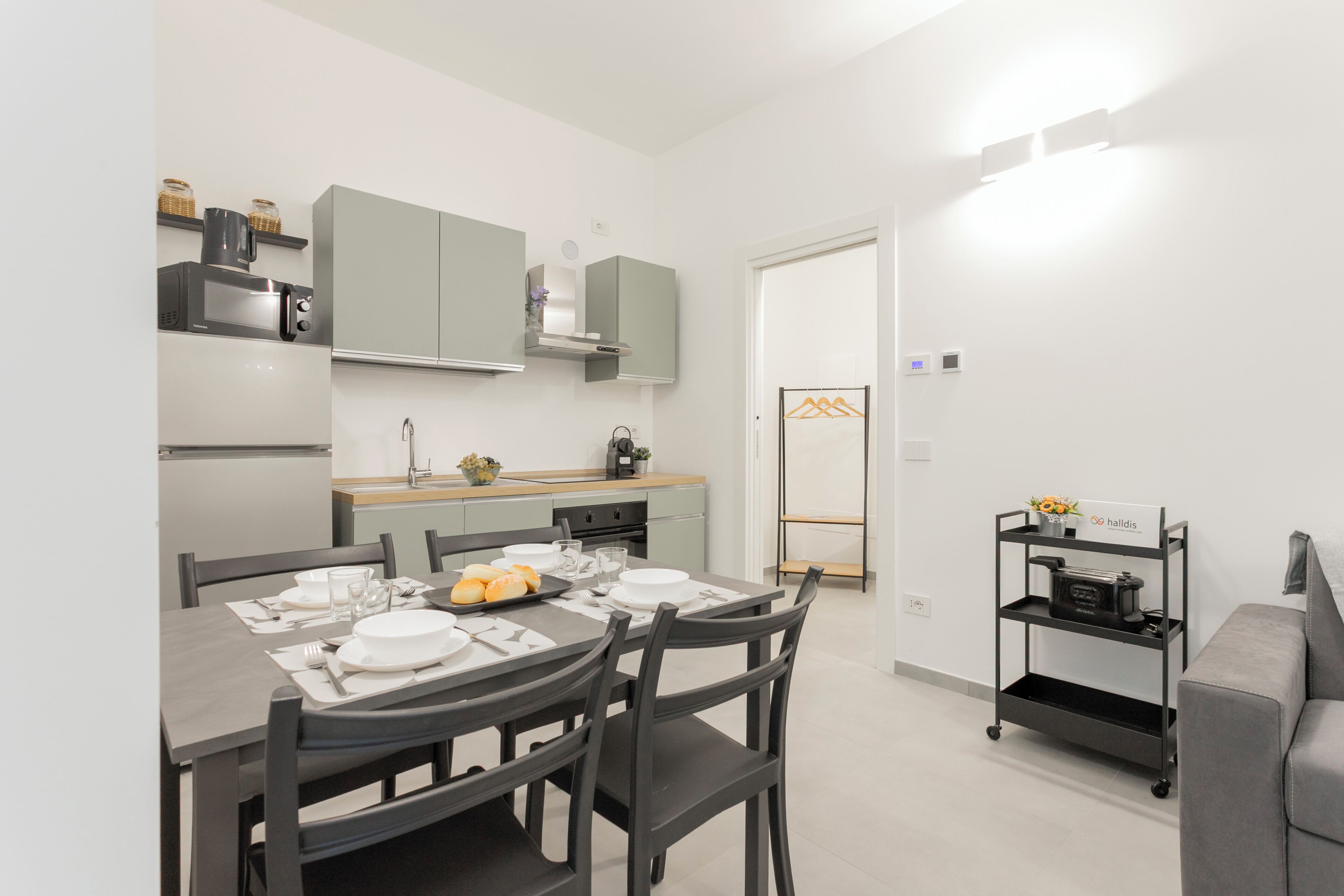 A compact kitchen with a dining table set for four, a microwave, and a coffee machine.