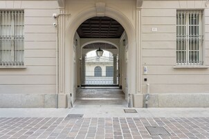 Una entrada de edificio con suelo de baldosas, arco de entrada y puerta de metal.