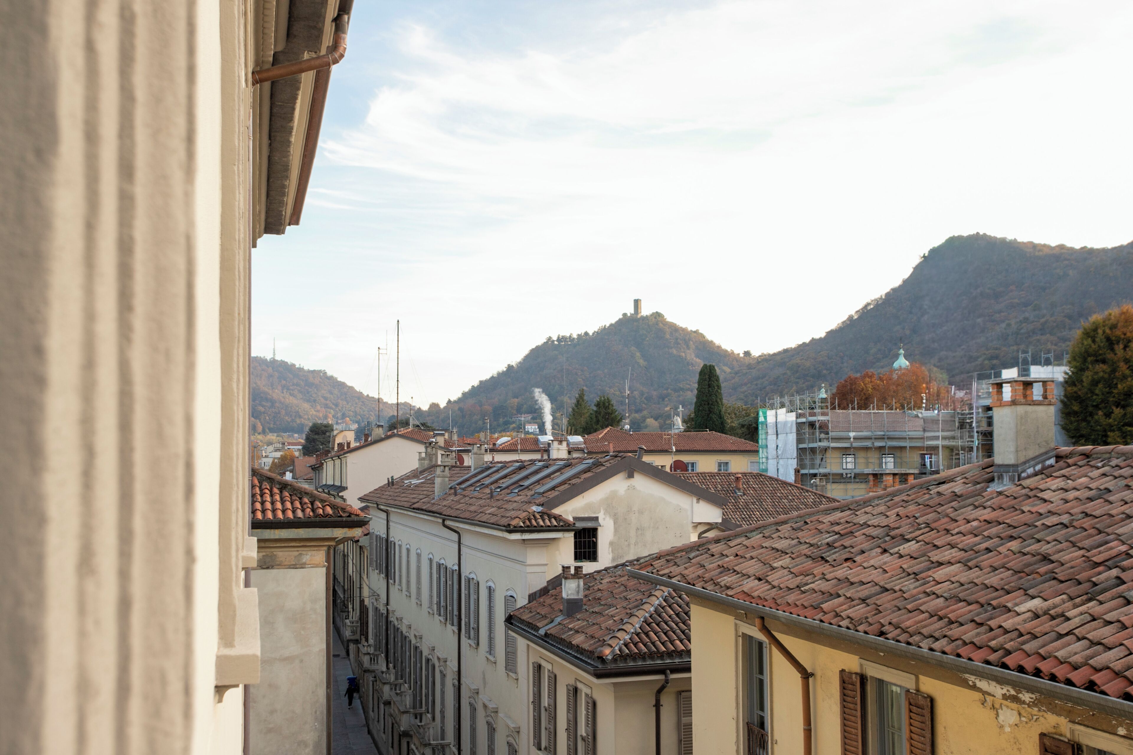 Una stretta via fiancheggiata da edifici, con una montagna sullo sfondo e cielo sereno.
