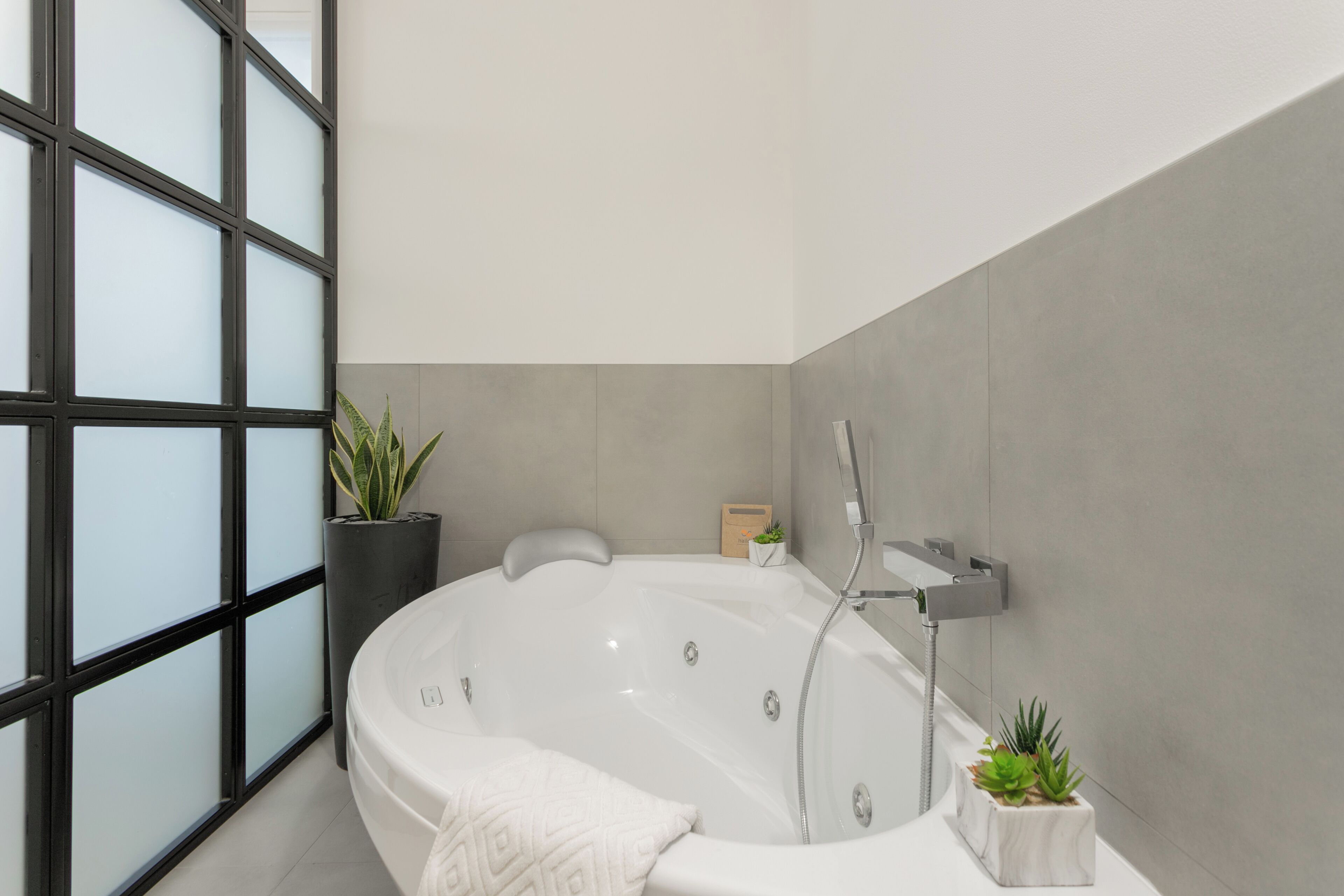 Ein modernes Badezimmer mit einer freistehenden Badewanne, einem Topfpflanzen und einer kleinen Holzschatulle.