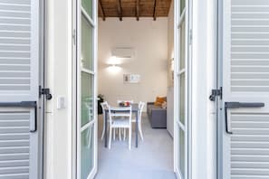 Une porte ouverte donne sur un espace repas comprenant une table, des chaises et un canapé.
