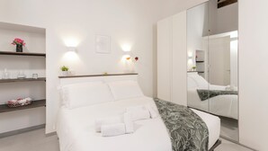 A modern hotel room with a bed, bedside tables, a mirror, and a wall-mounted light fixture. - VOLTA COLLECTION BY HALLDIS (Como)