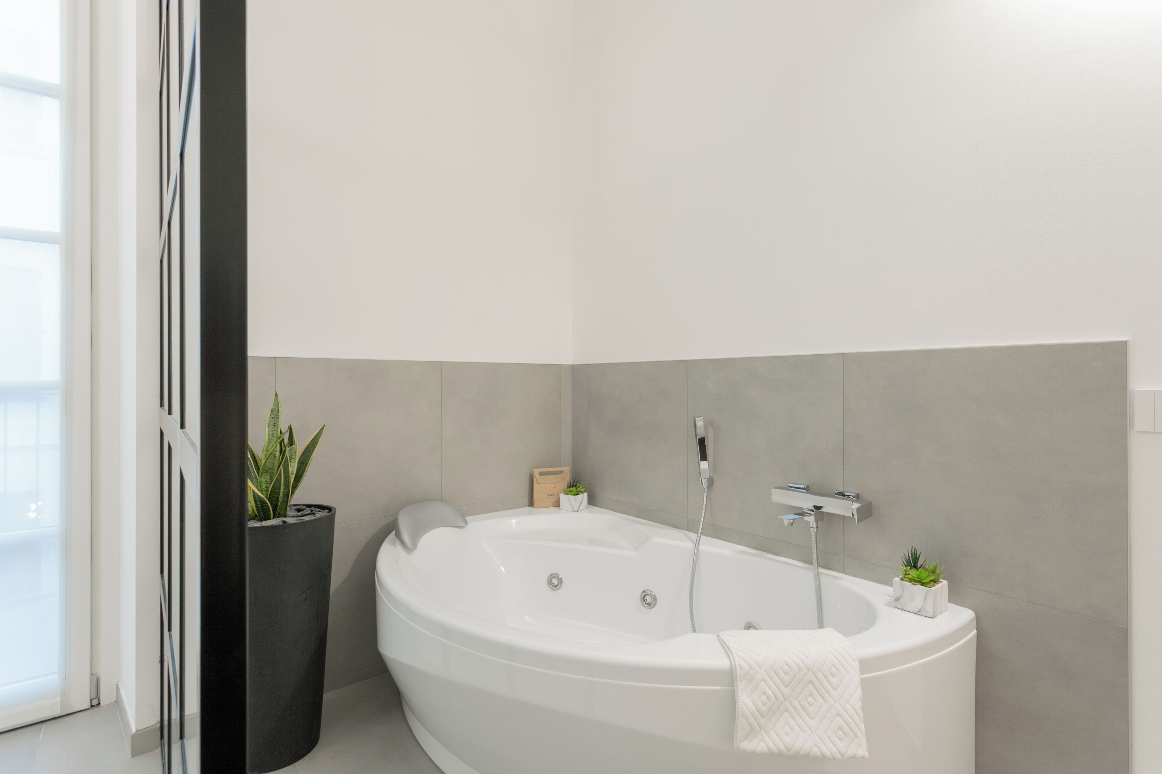 A modern bathroom with a freestanding bathtub, a potted plant, and a small shelf with toiletries.