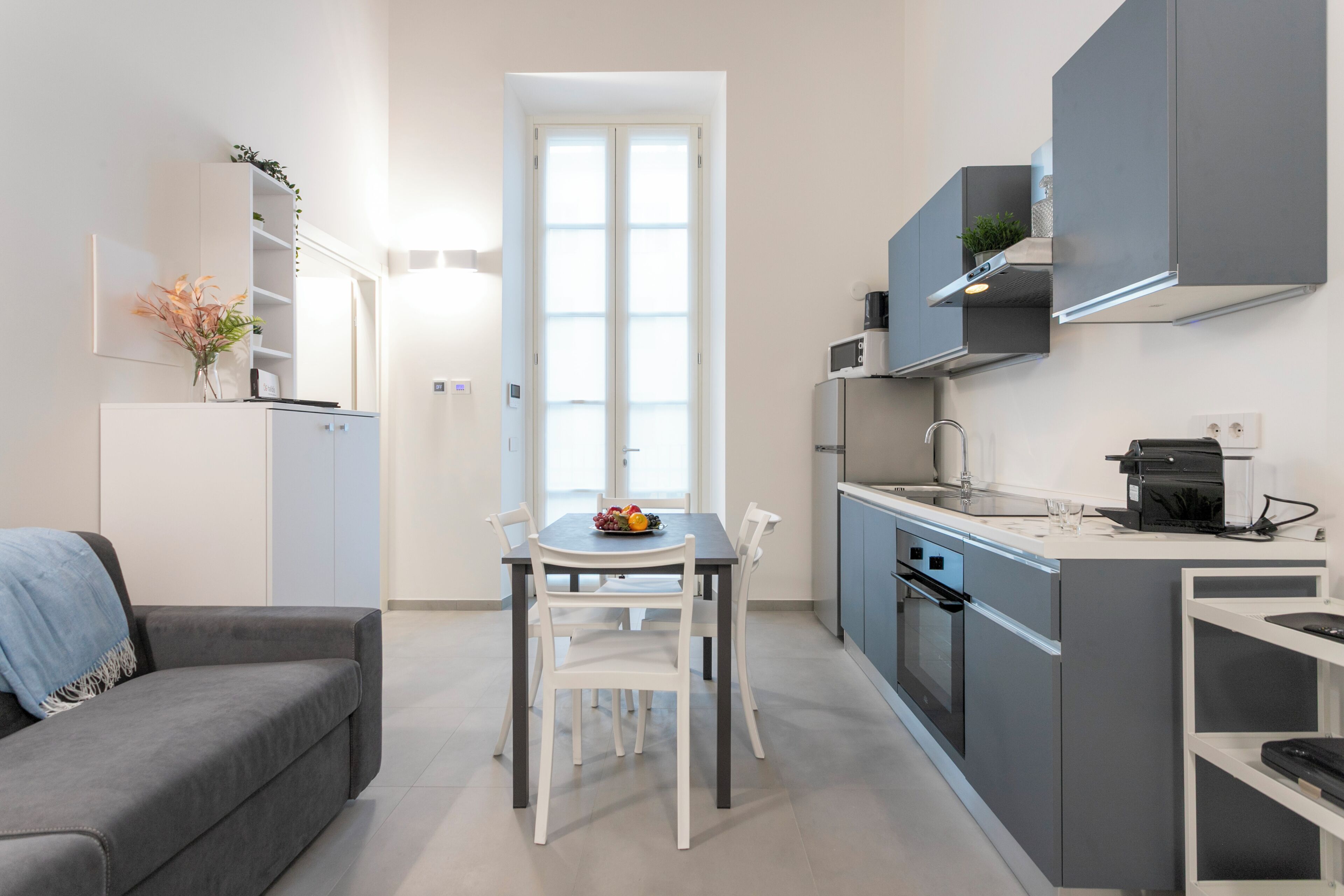 Une cuisine moderne équipée d’une table à manger, de chaises, d’un four encastré et d’une machine à café.