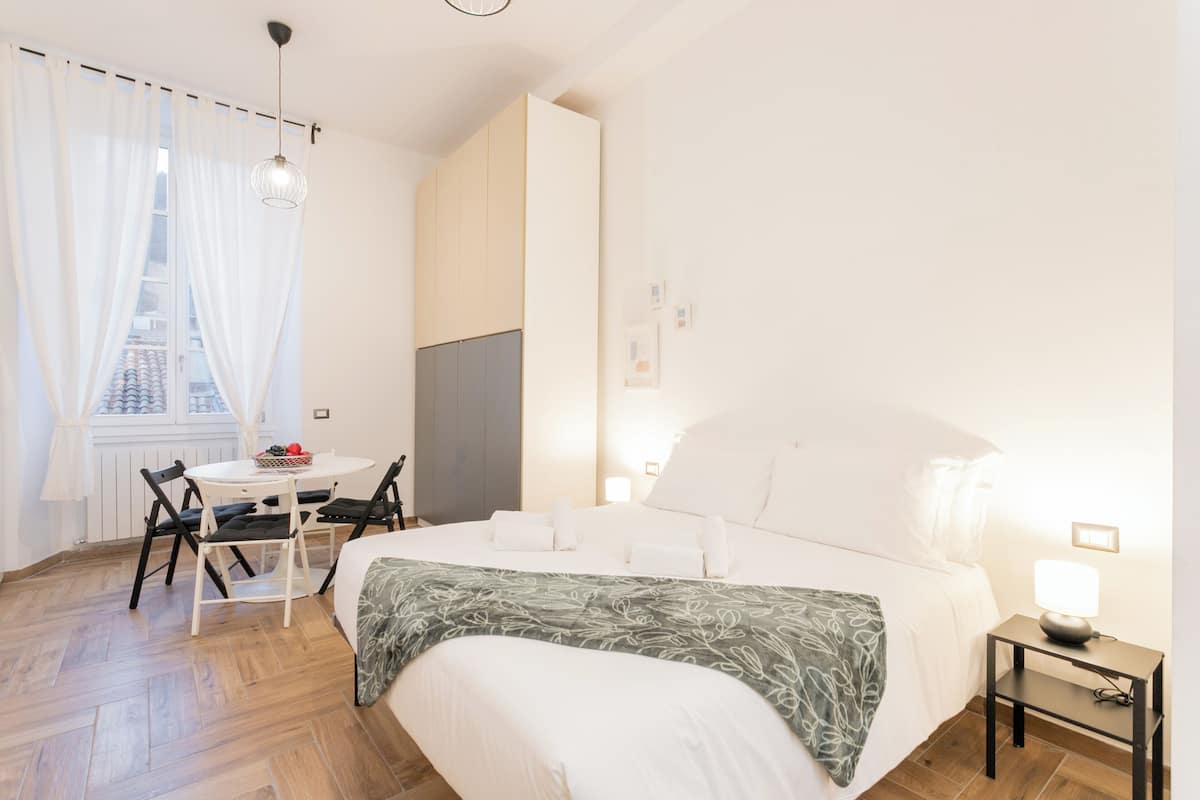 A bedroom with a bed, bedside table, lamp, and a window with curtains.
