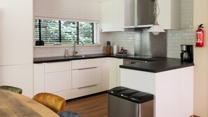 Una cucina moderna con mobili bianchi, un lavandino in acciaio inossidabile e una macchina da caffè.