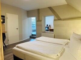 Un dormitorio con una cama grande, una puerta, una ventana y vistas a una zona de cocina.